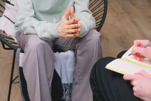 Close-up of a therapy session showing hands and a notepad, focus on interaction.