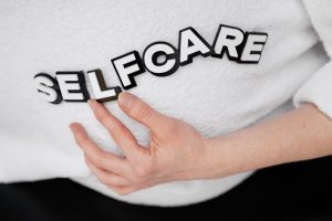 Close-up of a hand holding the word 'self-care' made with 3D letters on a white background.