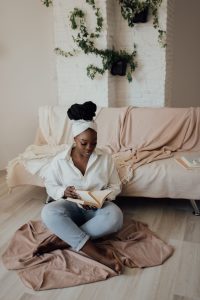 A woman enjoys reading on a cozy rug in an inviting home setting with greenery. 