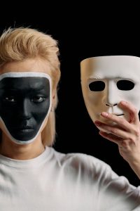 Creative portrait of a person with face makeup and a mask, conveying mystery and disguise.