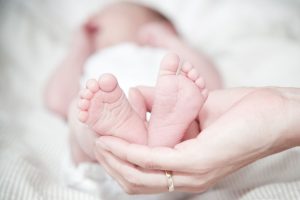 Tender photo of a mother's hands holding her newborn's feet, symbolizing love and care. 