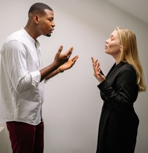 A couple engaged in a heated argument indoors, expressing strong emotions and gestures.